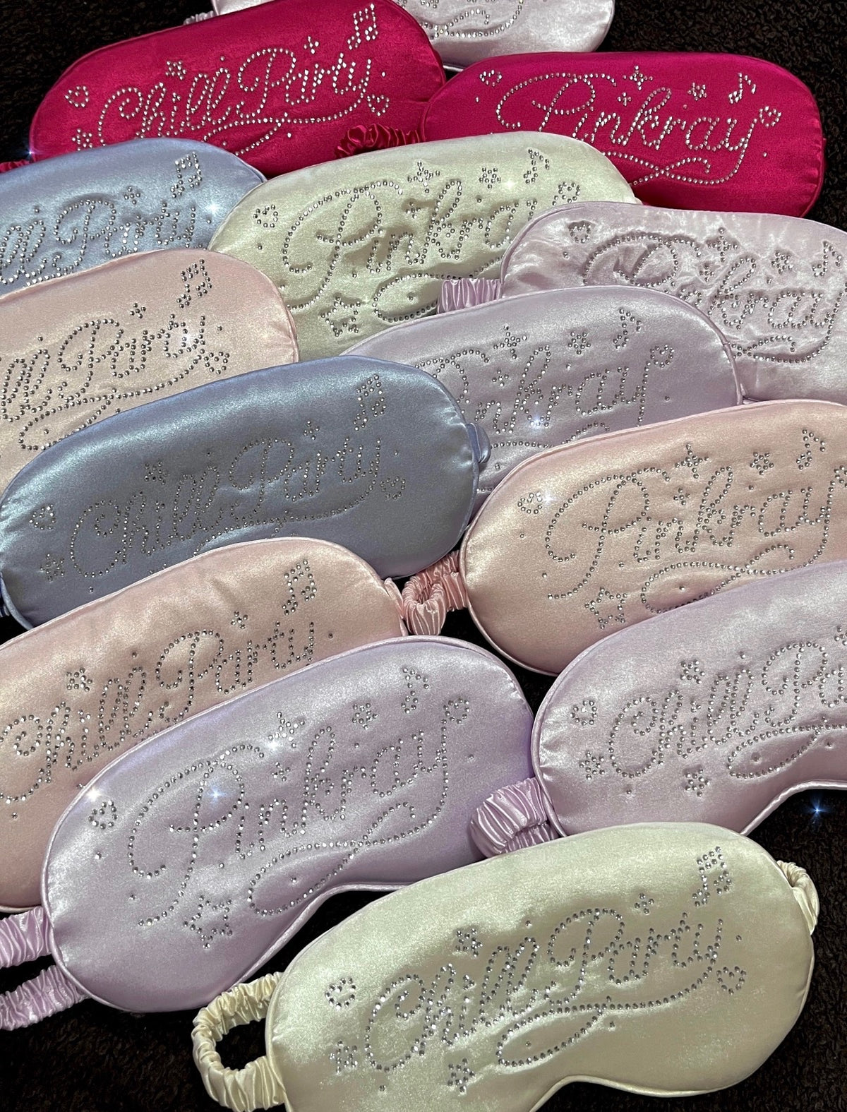A collection of satin sleep masks in various pastel and bright colors, each embellished with rhinestone-embroidered text reading 'Chill Party' and 'Pinkray'.